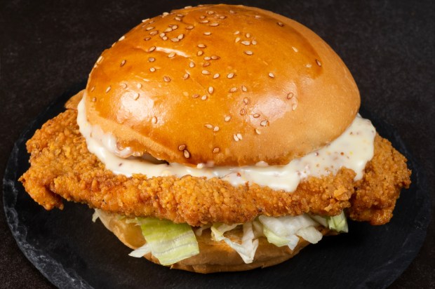a fried chicken sandwich on a bun with sesame seeds