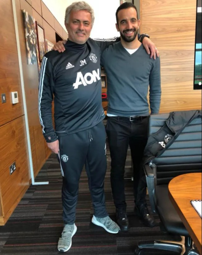 two men are posing for a picture and one has aon on his shirt