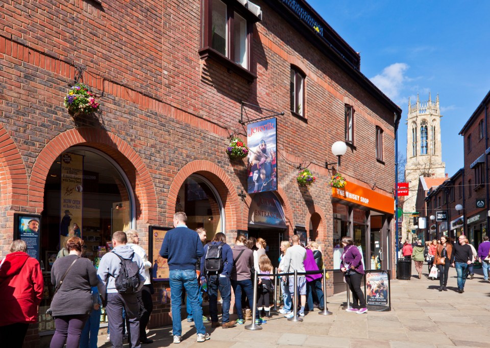 a group of people are standing outside of a store called the ticket shop