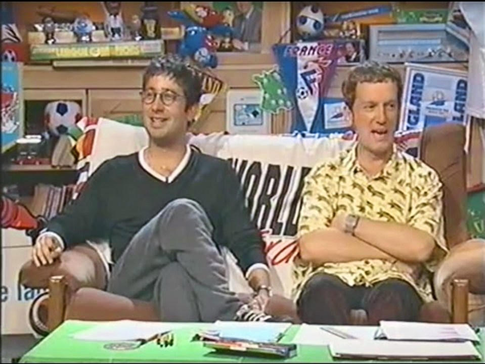 two men sit on a couch with a blanket that says world on it