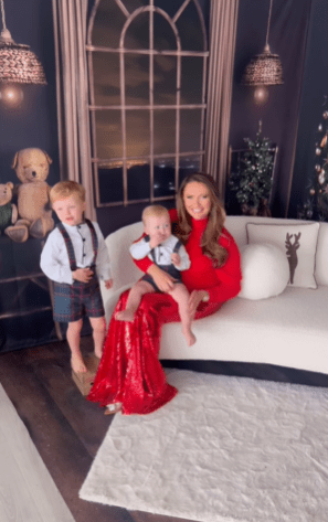 a woman in a red dress is sitting on a white couch with two children