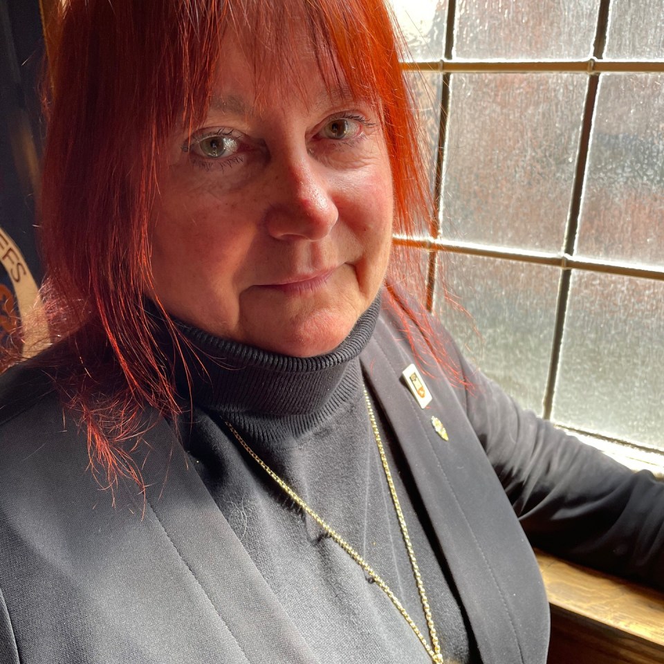 a woman with red hair is wearing a black turtleneck and a gold necklace