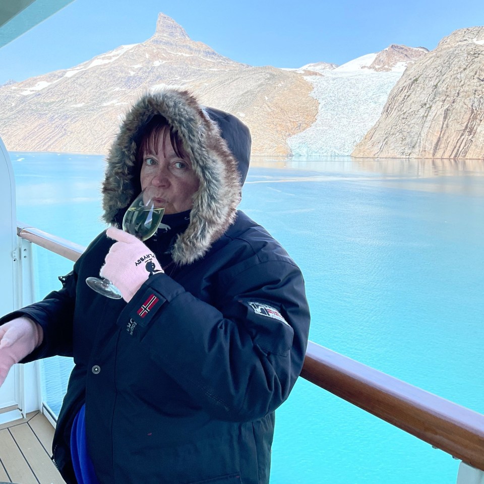 a woman wearing a napapijri jacket drinks from a glass