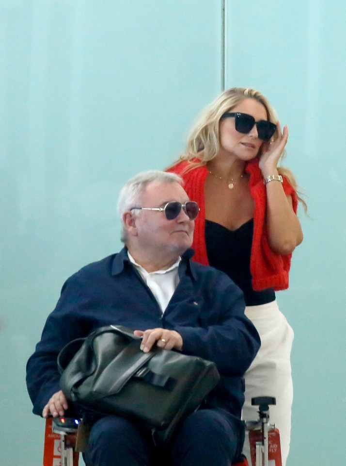 a woman standing next to a man in a wheelchair
