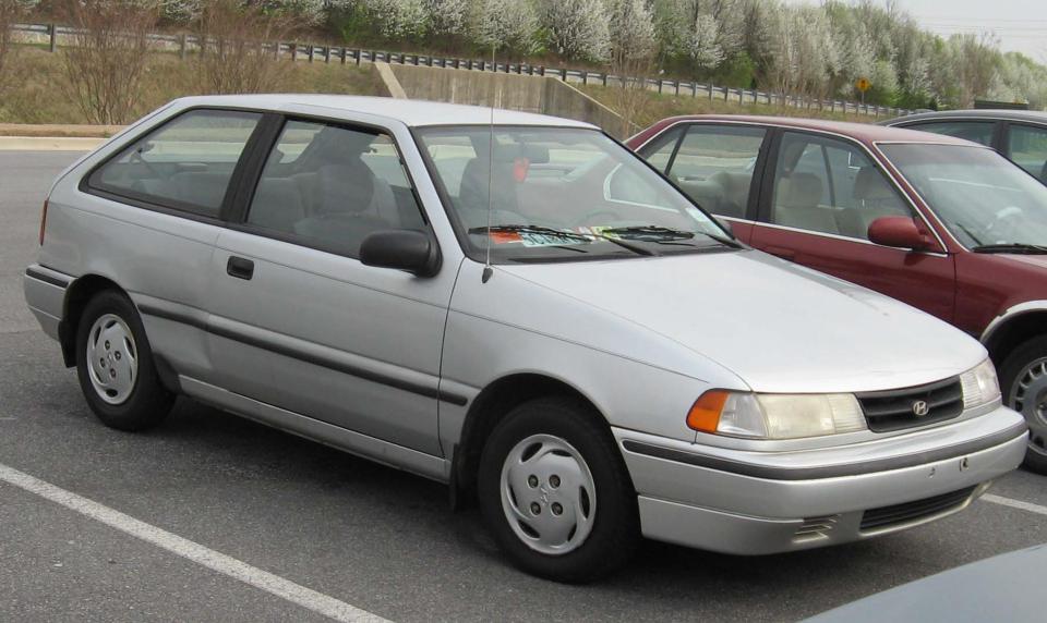 a silver car is parked in a parking lot next to a red car