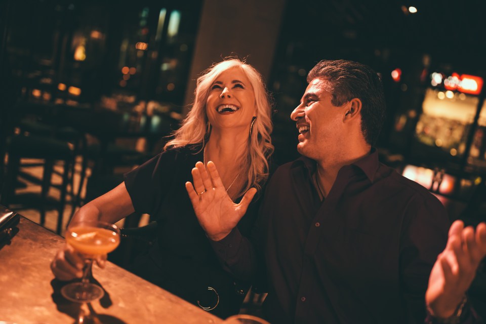 a man and a woman are sitting at a bar laughing