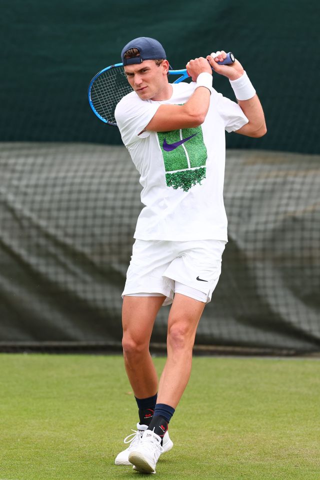 a man in a white nike shirt is swinging a tennis racquet