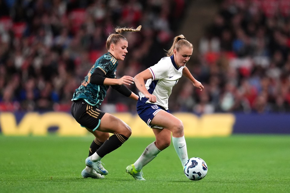 two female soccer players on a field with one wearing a nike jersey