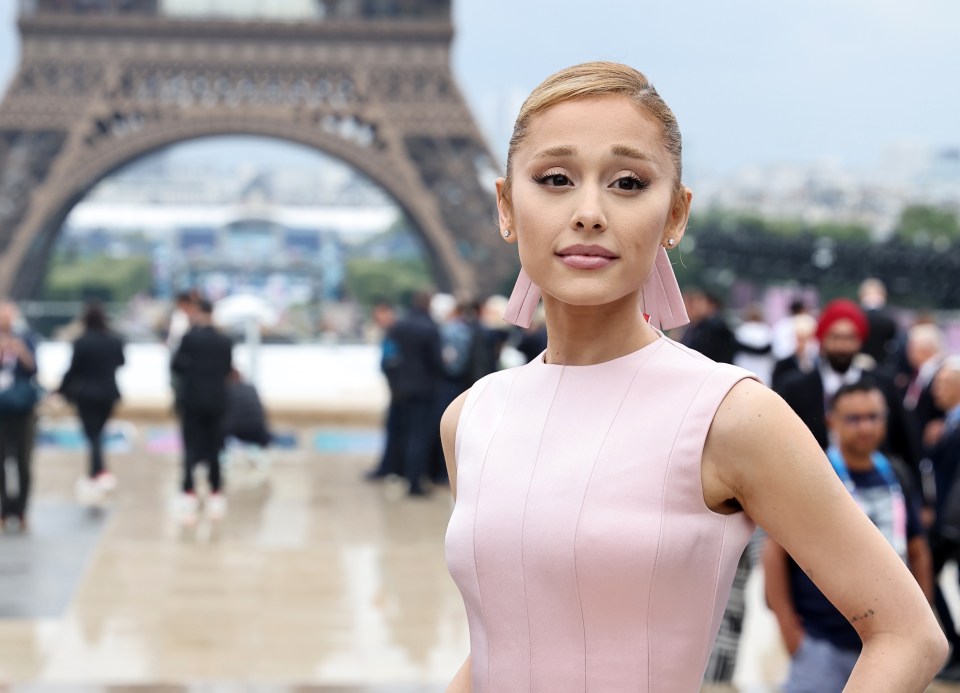 a woman in a pink dress stands in front of the eiffel tower