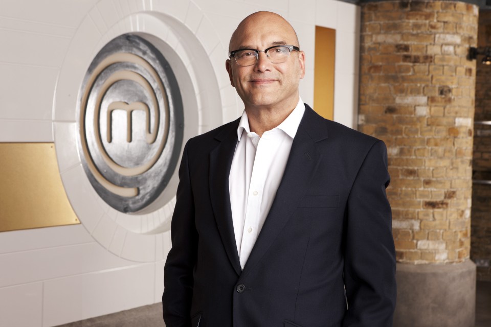 a man in a suit stands in front of a masterchef logo