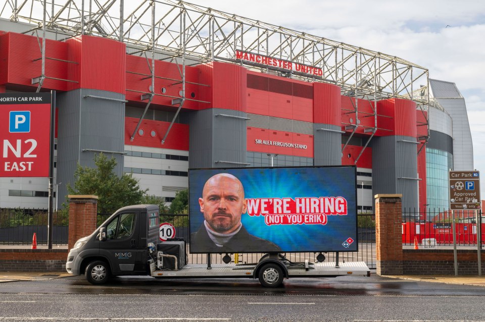 a domino 's pizza truck is parked in front of manchester united stadium