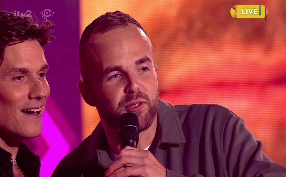 a man speaking into a microphone in front of a screen that says live