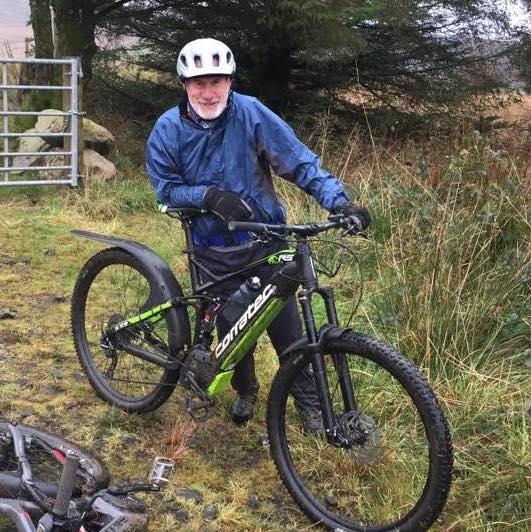 a man is standing next to a mountain bike on a rocky hillside .