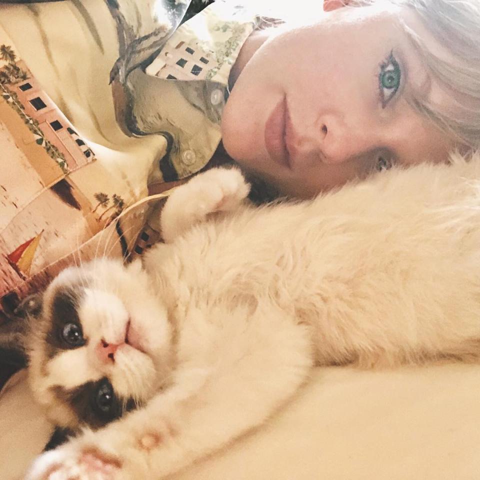 a woman with green eyes laying next to a white cat