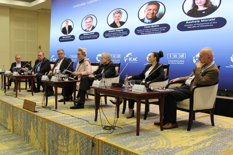 a group of people sit at tables in front of a sign that says icac institute