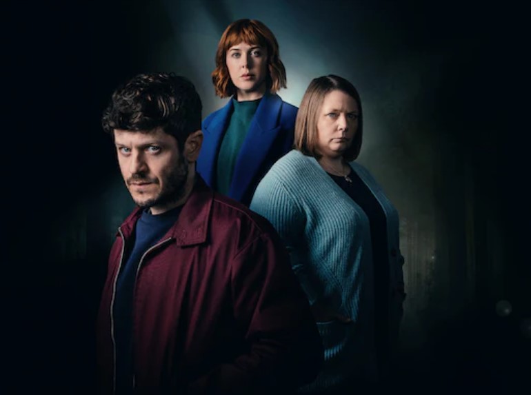a man and two women are standing next to each other in a dark room