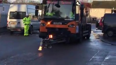 a scanska truck is driving down a wet street .