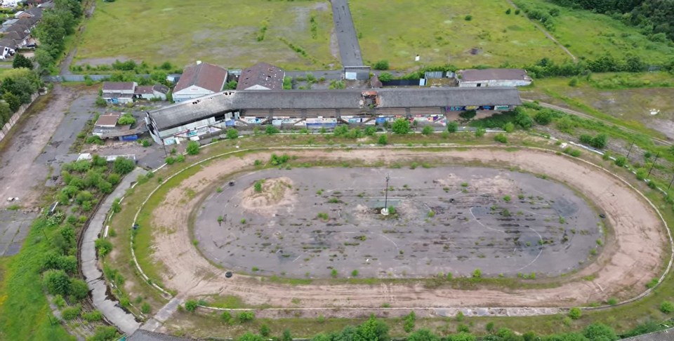 an aerial view of a race track with a large building in the background