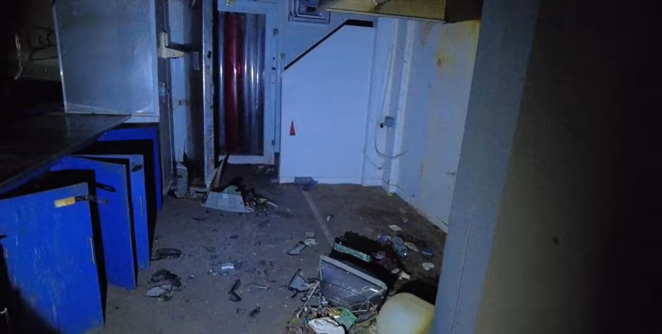 a room with a lot of trash on the floor and a door that says ' emergency exit ' on it