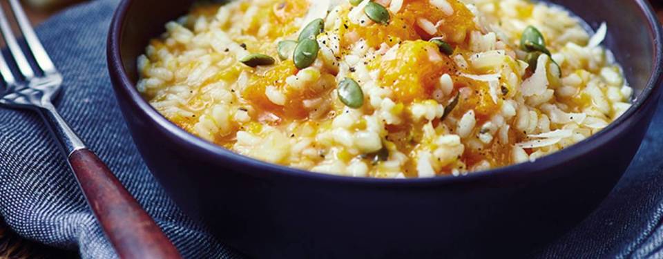 a bowl of risotto with pumpkin seeds and cheese