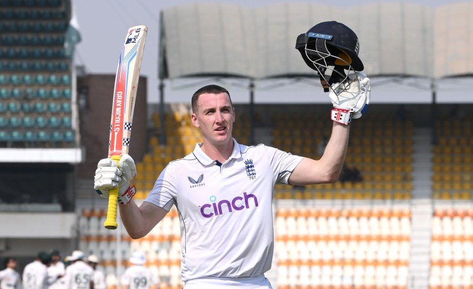 a man in a cinch shirt holds up his bat