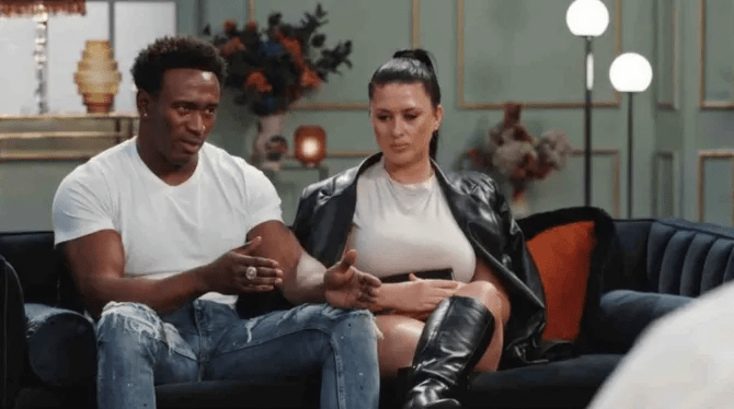 a man and a woman are sitting on a couch talking to each other .