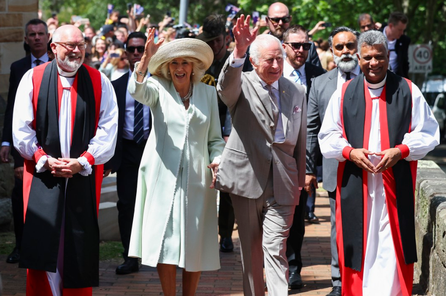 a man in a suit and a woman in a white coat are walking with two priests