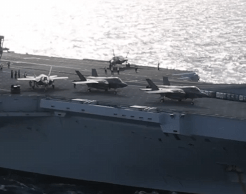 three fighter jets are parked on the deck of a large ship