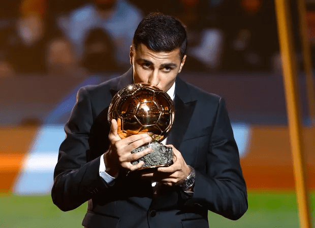 a man in a suit is holding a trophy and kissing it