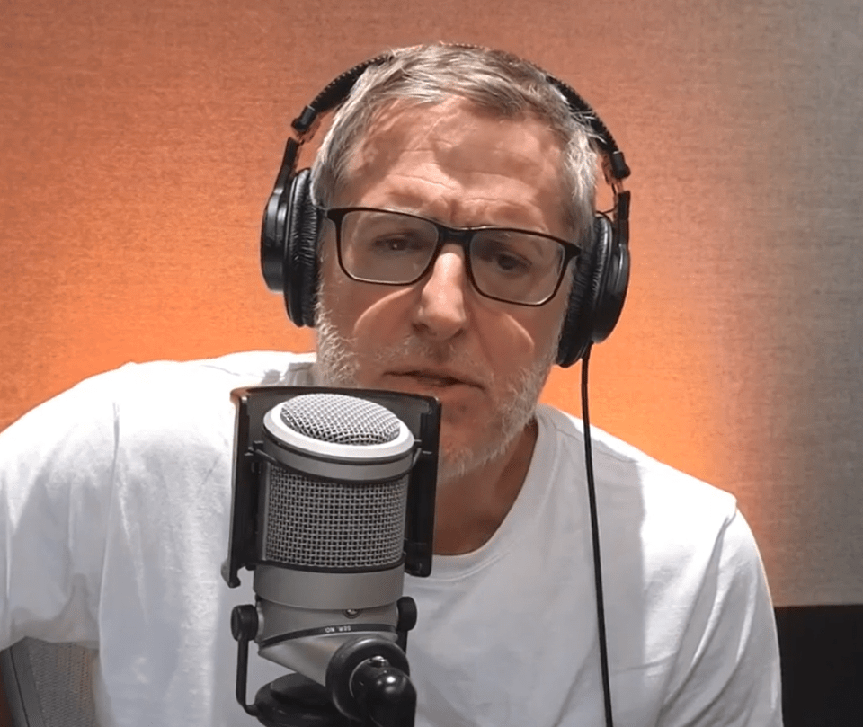 a man wearing glasses and headphones stands in front of a microphone