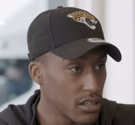 a man wearing a black hat with a jaguar on it
