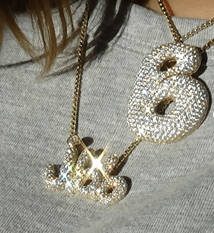 a person wearing a necklace with the letter b on it