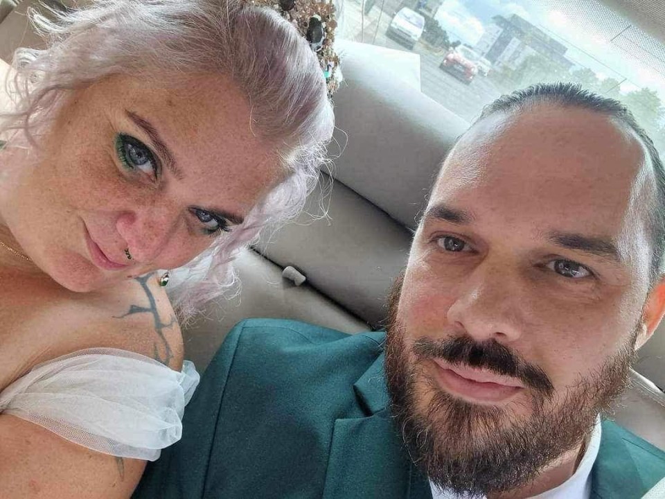 a bride and groom are posing for a picture in the back seat of a car .