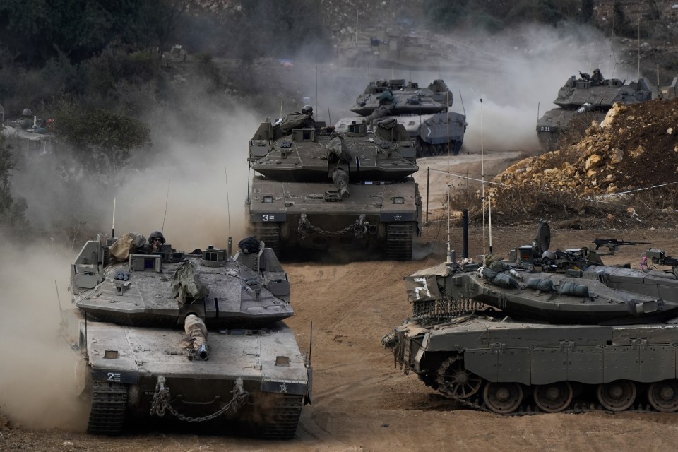 a group of military tanks are driving down a dirt road
