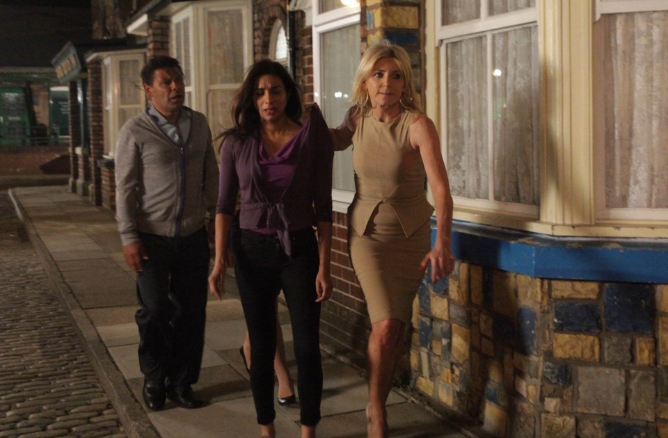 a man and two women are walking down a cobblestone street