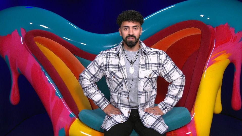 a man in a plaid shirt is sitting in a colorful chair