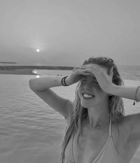 a woman in a bikini is standing in the water covering her eyes with her hands .