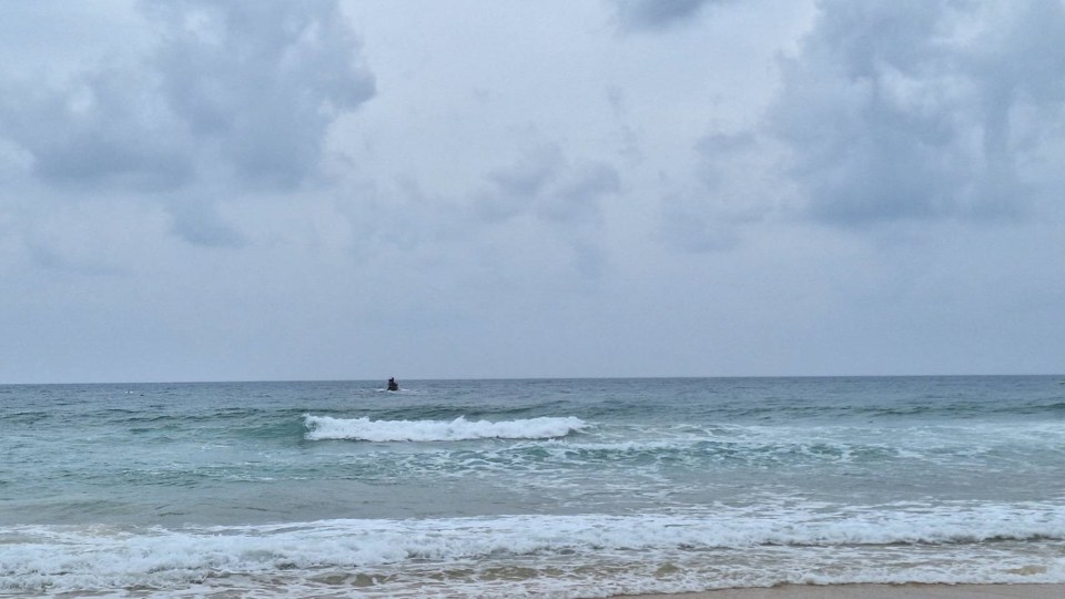 a person riding a wave in the ocean on a cloudy day