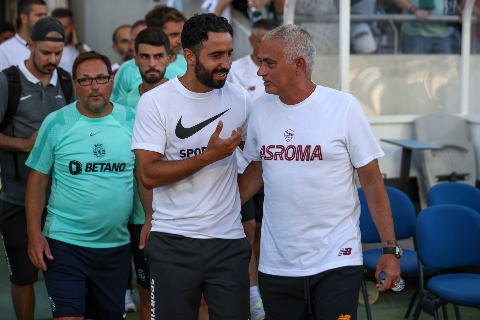 a man wearing a white asroma shirt talks to another man