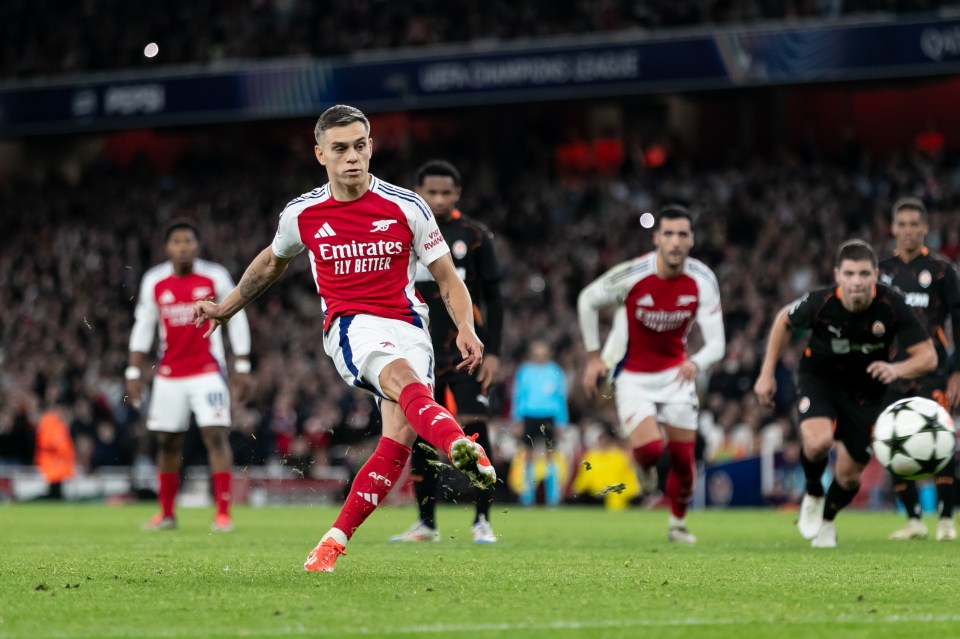 a soccer player wearing an emirates jersey kicks the ball