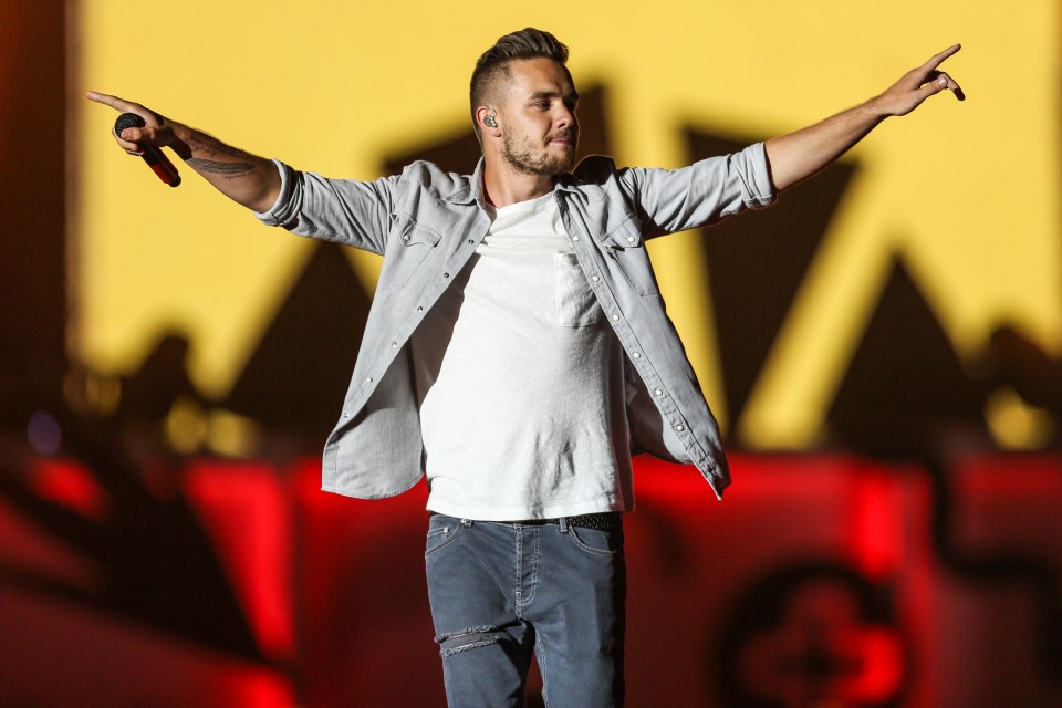 a man singing into a microphone with his arms outstretched