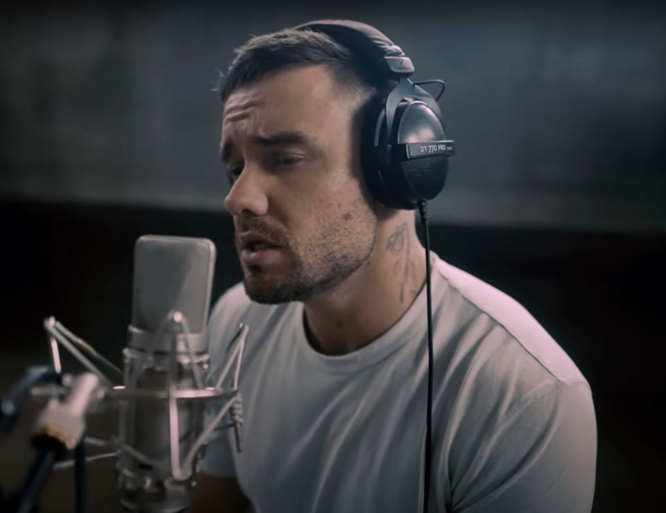 a man wearing a pair of dt 750 pro headphones sings into a microphone