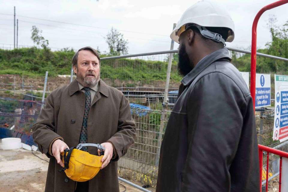 a man wearing a hard hat is talking to another man