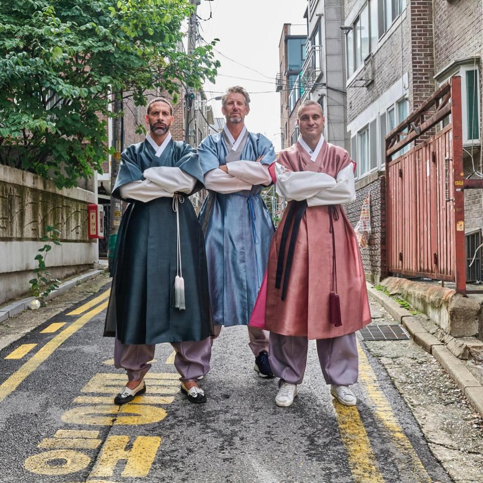 three men are standing on a street with a yellow sign that says ' high ' on it