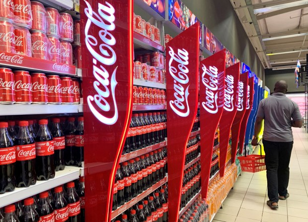 a man walking down a coca cola aisle in a store