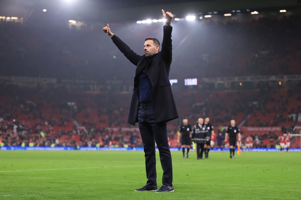 a man stands on a soccer field with his arms in the air