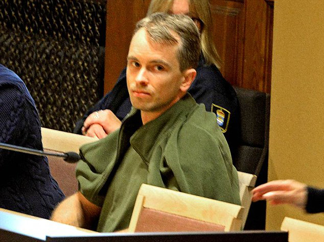 a man in a green jacket sits in a courtroom
