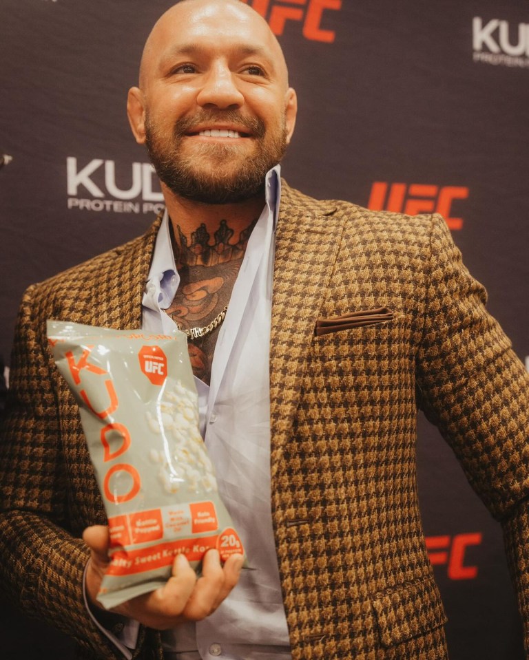 a man in a suit is holding a bag of ufc popcorn
