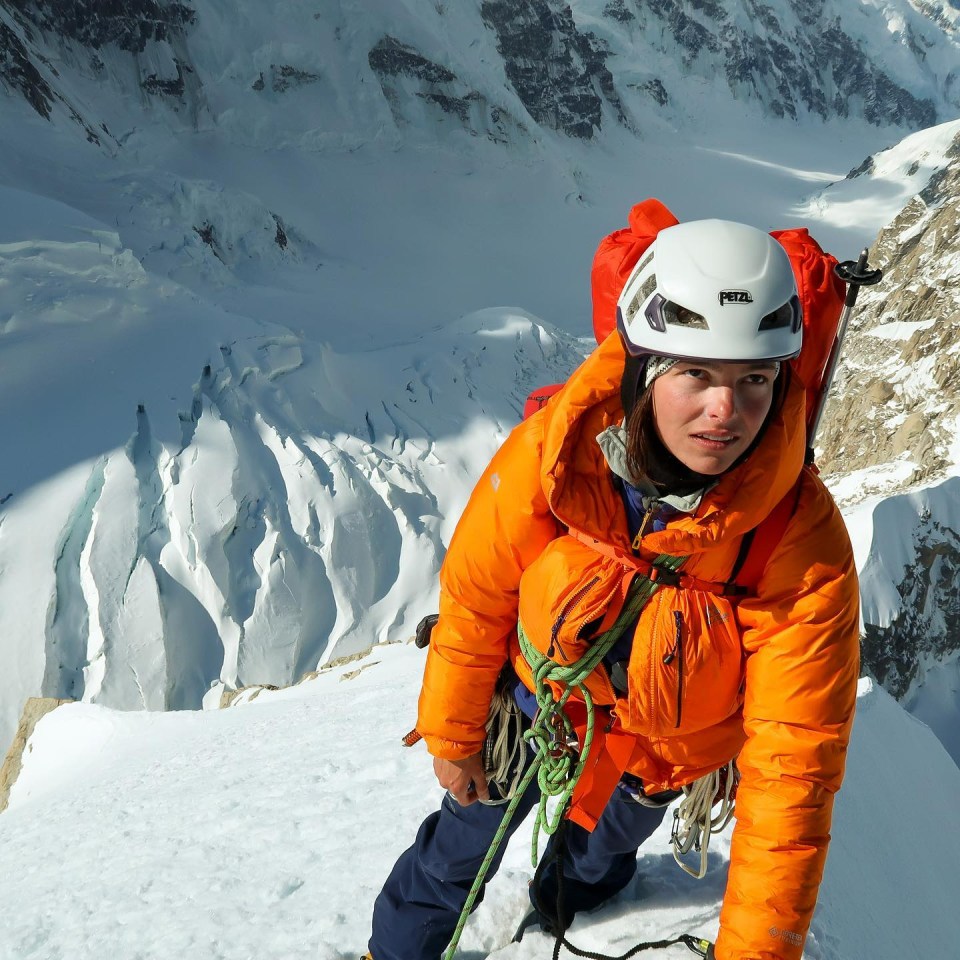 a person wearing a petzl helmet stands in the snow