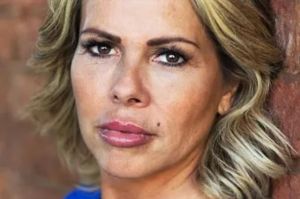 a close up of a woman 's face with a brick wall in the background .